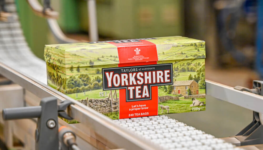 特写照片：制造工厂内，传送带上的一盒 Taylors of Harrogate 茶