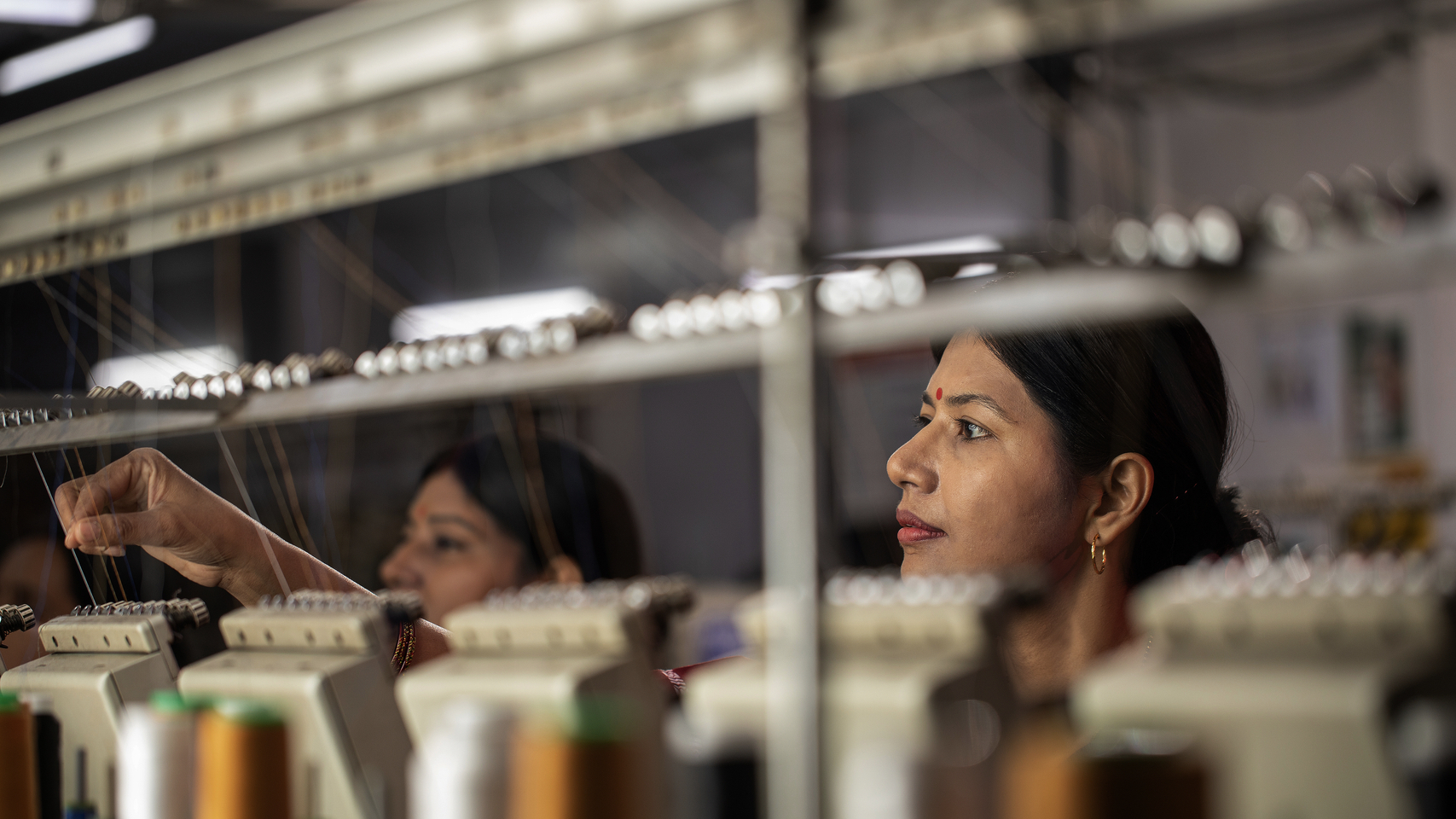 女缝纫工正在给工业缝纫机穿线 