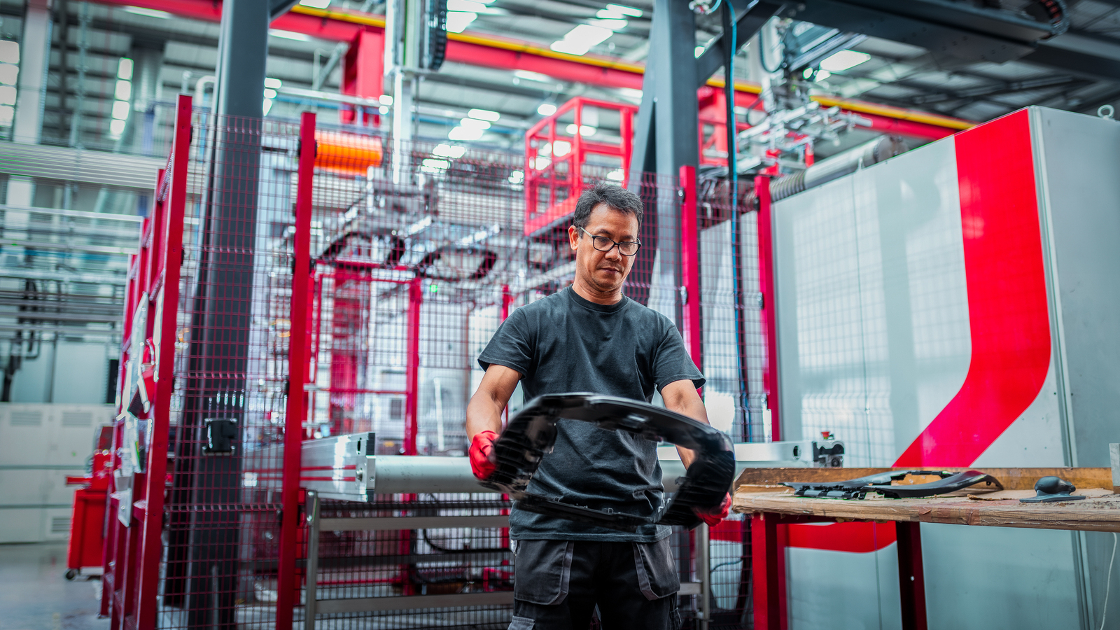 Worker inspecting moulds product by robotic moulding machine in automotive parts factory_Plastic Injection_GettyImages-1603723017_Edited.jpg