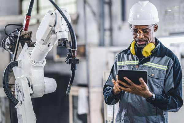Technician controlling a robotic arm in a factory  