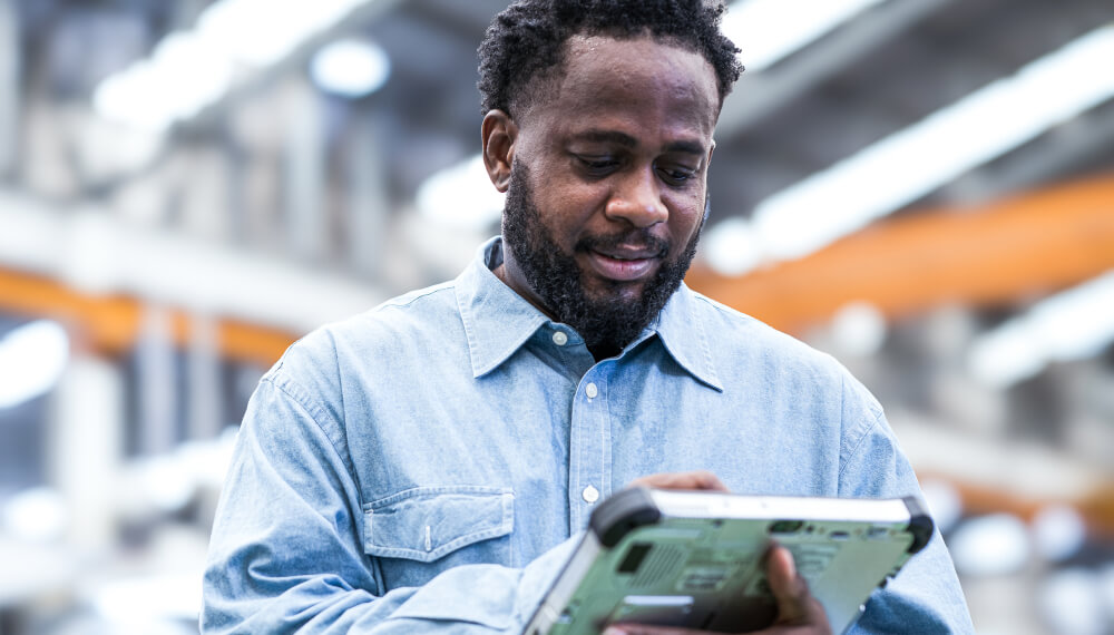 商人在一间制造工厂内手持平板电脑